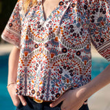 Multi-colored arched floral print top with a v-neckline and short sleeves.