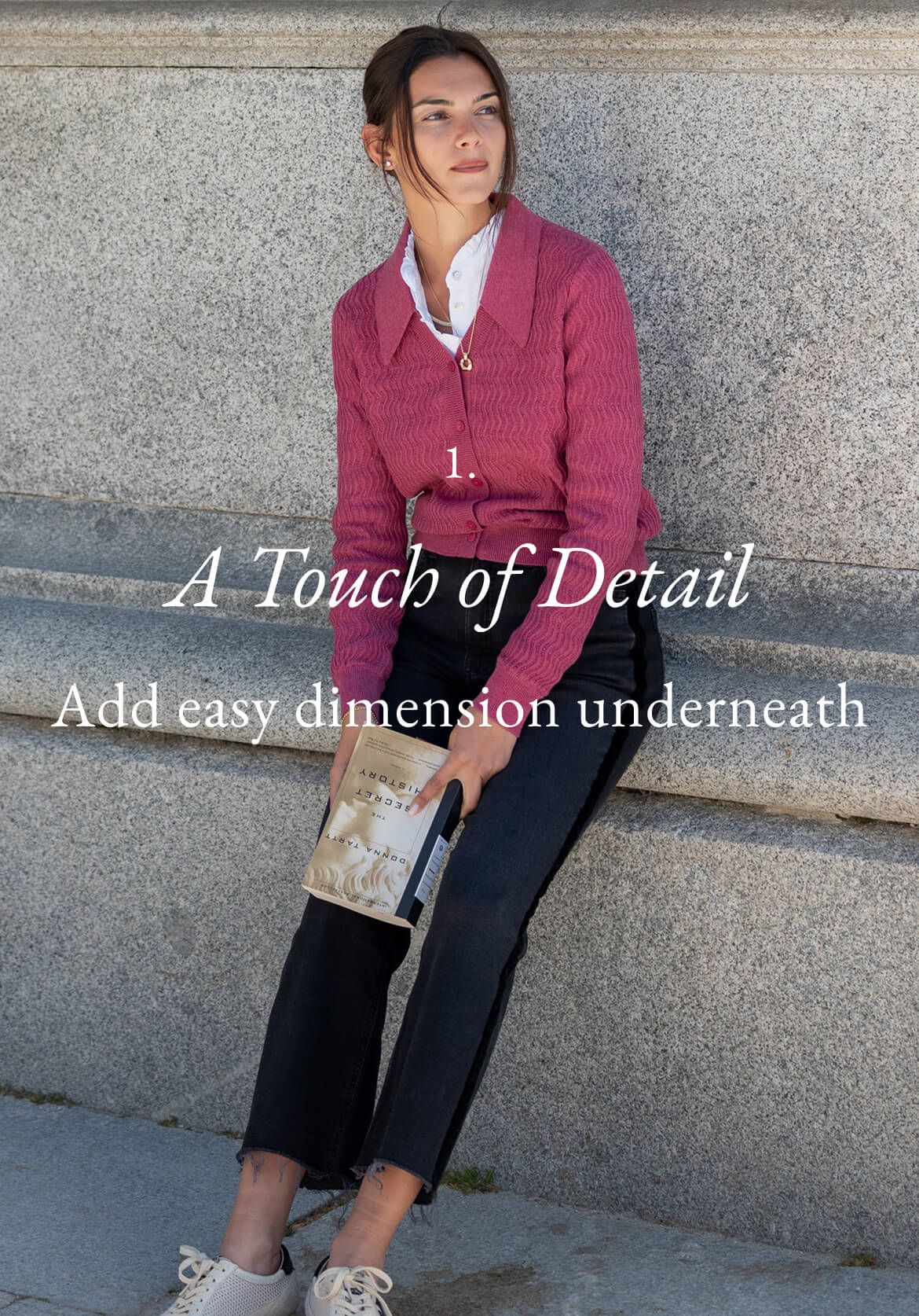 A woman leans against a stone wall wearing a pink ribbed cardigan over a white collared shirt and black cropped trousers. Text: A Touch of Detail. Add easy dimension underneath