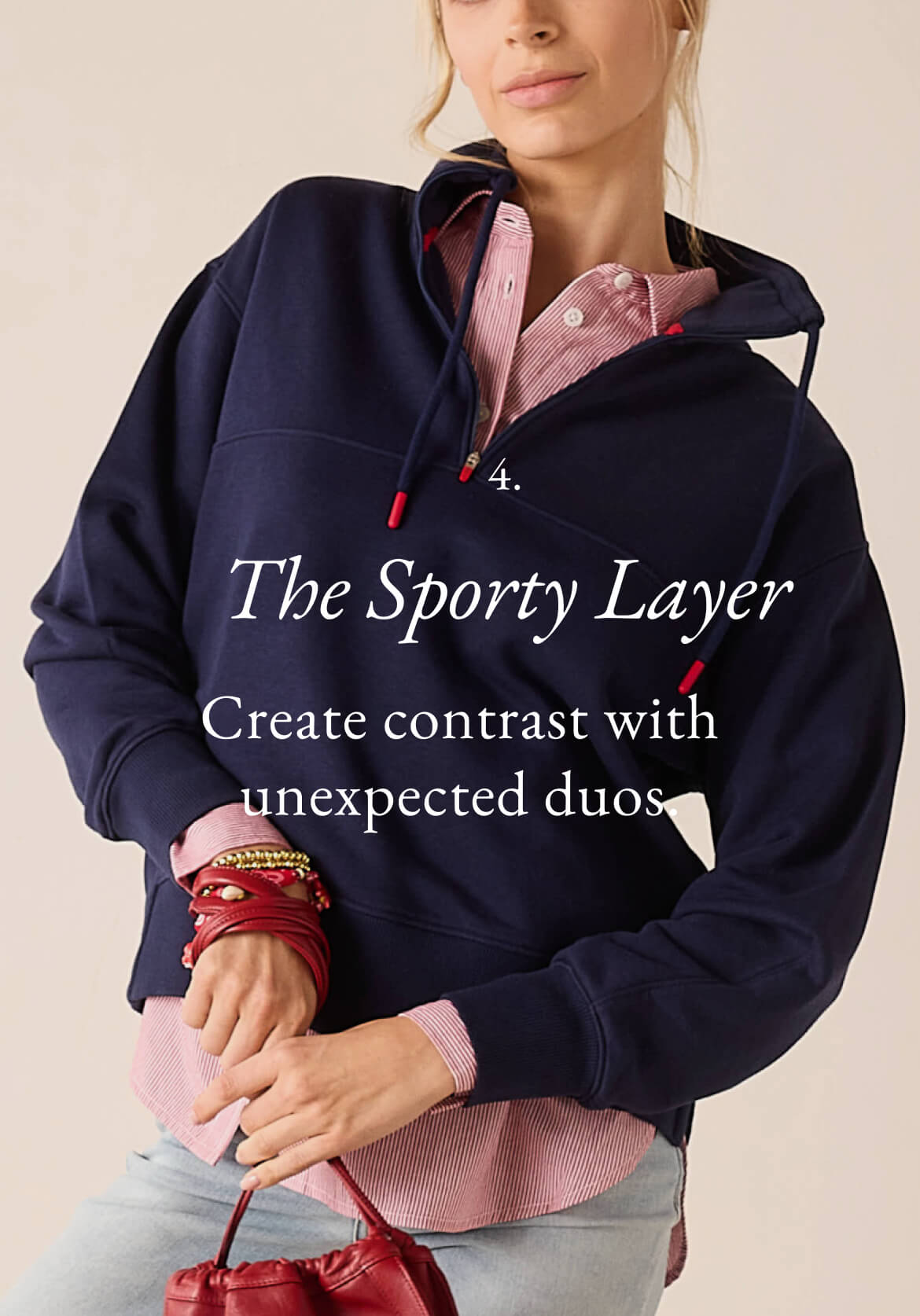 A woman wearing a navy blue hooded sweatshirt over a pink striped button-down shirt. Text: 'The Sporty Layer Create contrast with unexpected duos.'