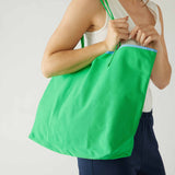 woman holding le canvas tote in green on shoulder