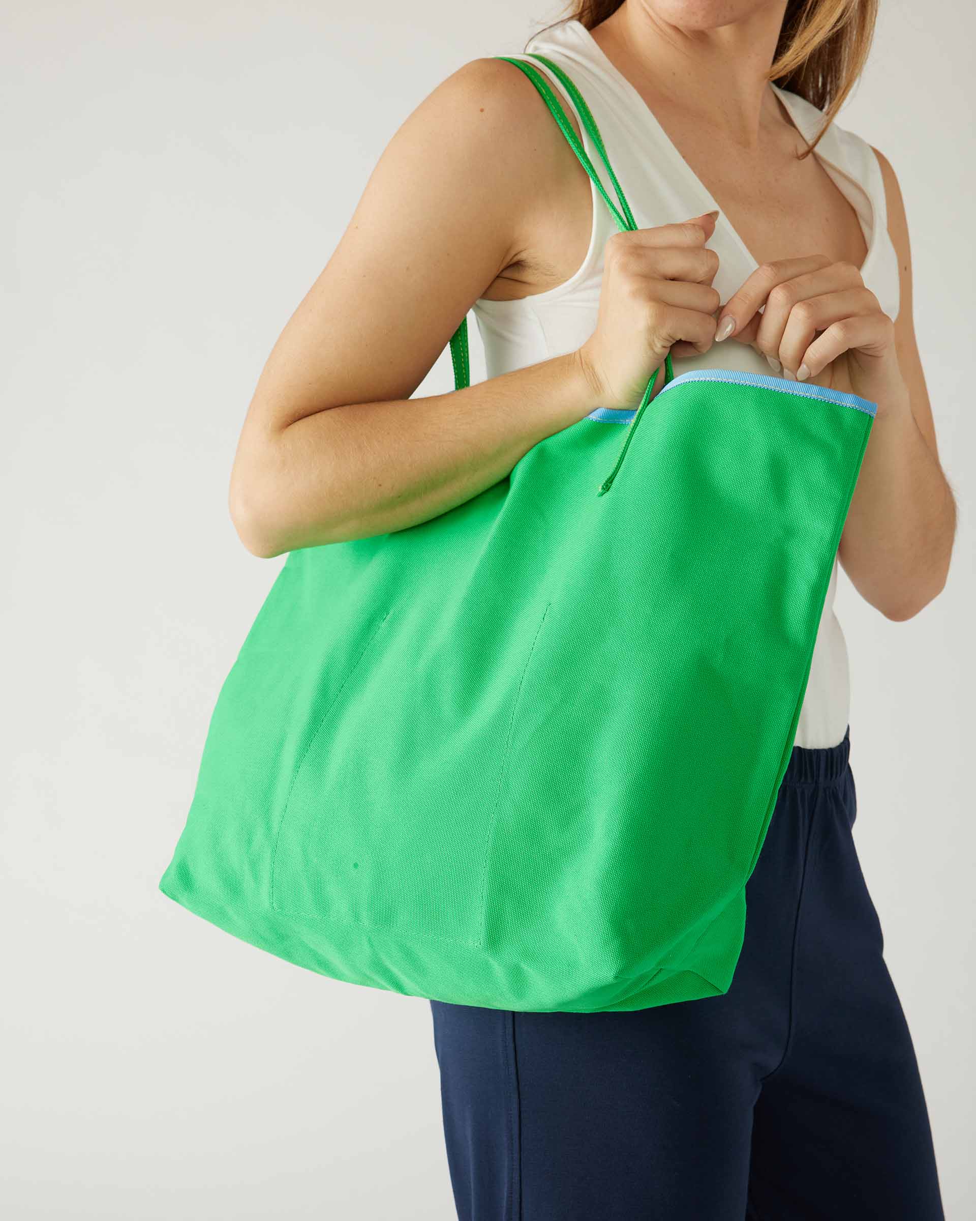 woman holding le canvas tote in green on shoulder