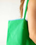 close up detail of woman holding le canvas tote in green with blue trim
