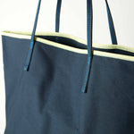 close up of le canvas tote in navy with green trim