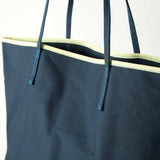 close up of le canvas tote in navy with green trim