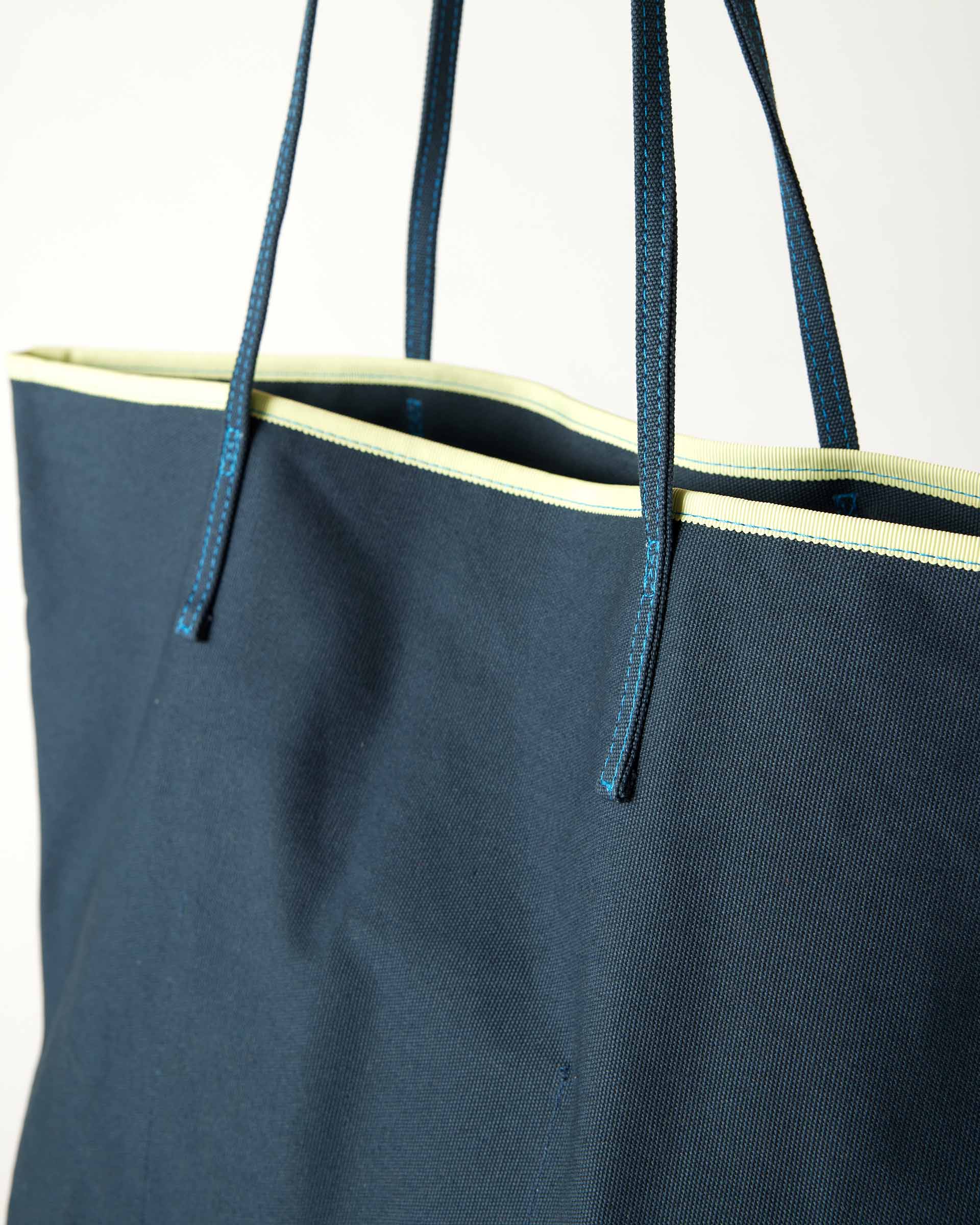 close up of le canvas tote in navy with green trim