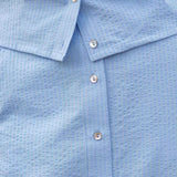 Close-up of a blue textured shirt with buttons