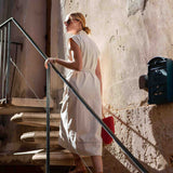 Woman in a white dress standing on a staircase with a textured wall behind her