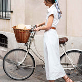 Woman in white outfit with bicycle on a city street