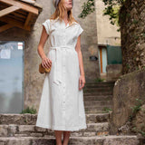Woman in a white dress standing on stone steps outdoors