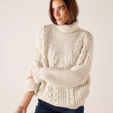 Ladies' travel-ready cream cable knit turtleneck sweater with a relaxed fit.