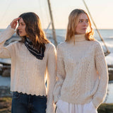 Cream cable knit turtleneck sweater with a textured ribbed hem.