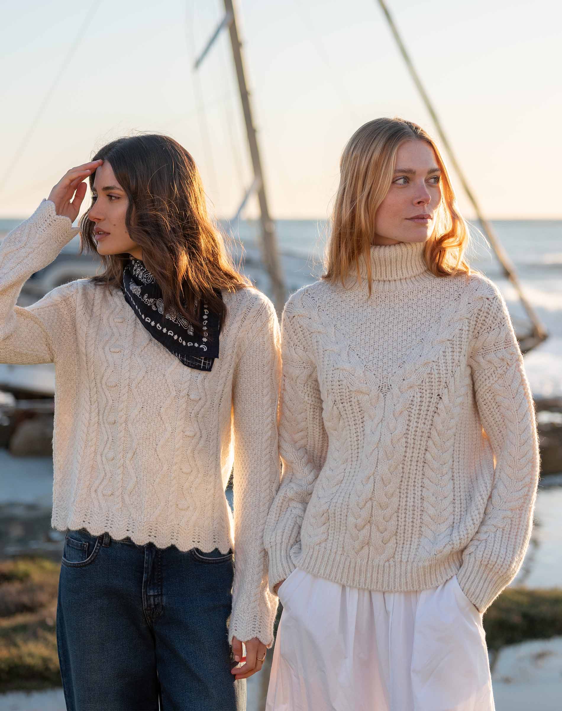 Cream cable knit turtleneck sweater with a textured ribbed hem.