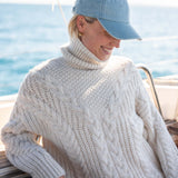 Cream cable-knit turtleneck sweater with a chunky knit design.