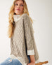 closeup of woman showcasing mersea lisbon traveler sweater in driftwood and seasalt sitting on stool