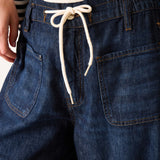 Close-up of blue denim pants with a drawstring on a neutral background