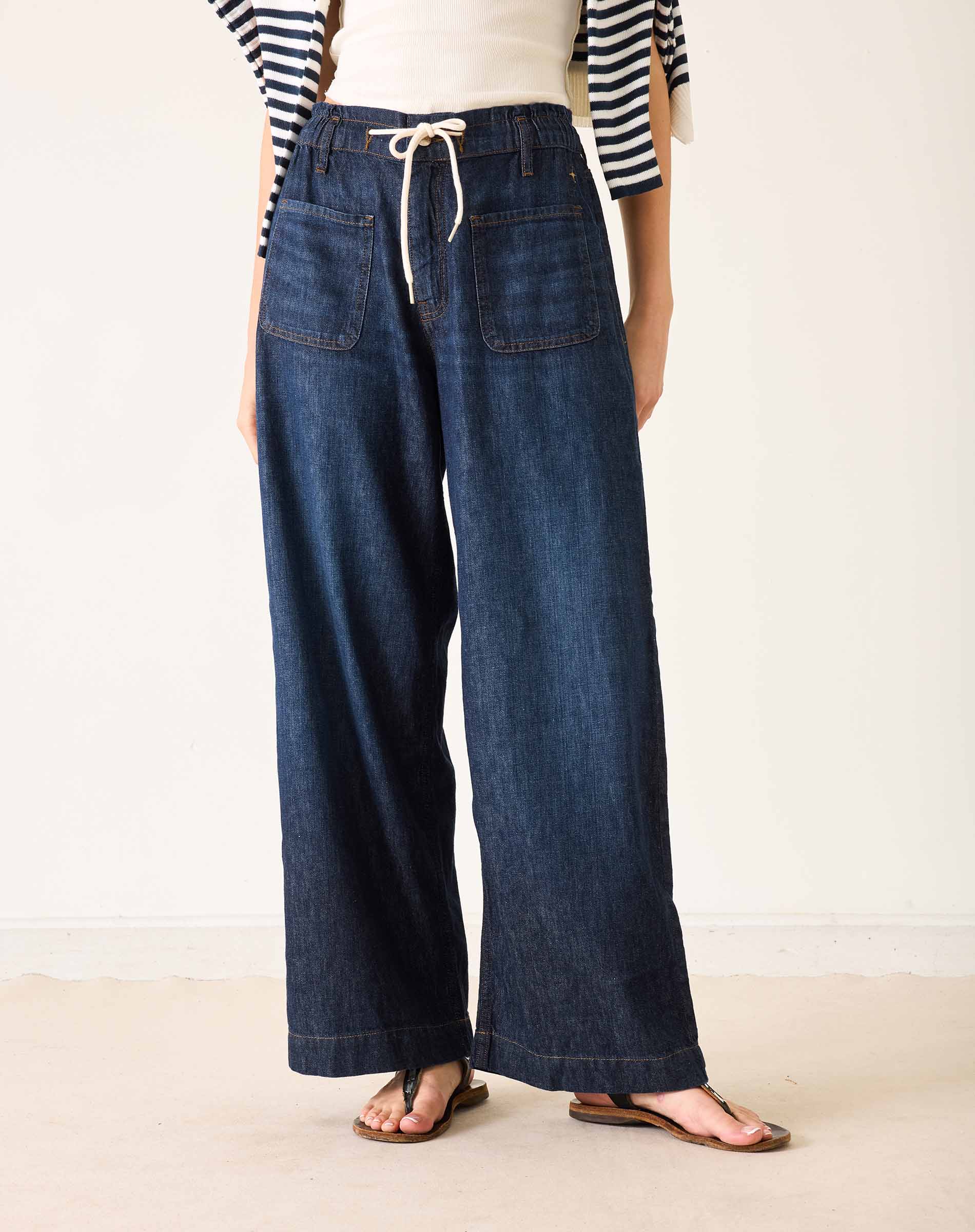 Person wearing wide-leg jeans and a striped shirt on a plain background