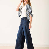Woman wearing a striped shirt and wide-leg jeans against a white background