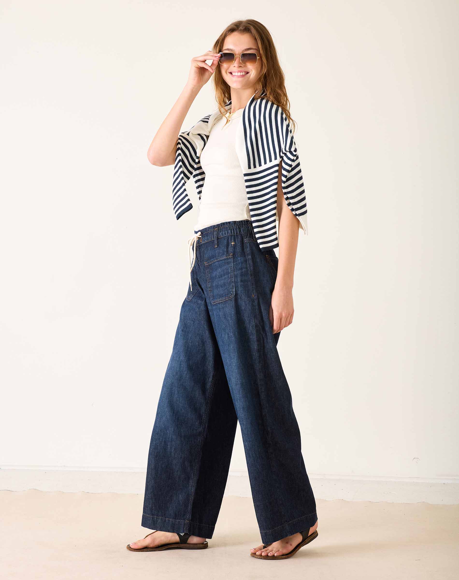 Woman wearing a striped shirt and wide-leg jeans against a white background