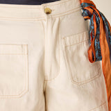 Beige shorts with a colorful scarf tied around the waist on a neutral background