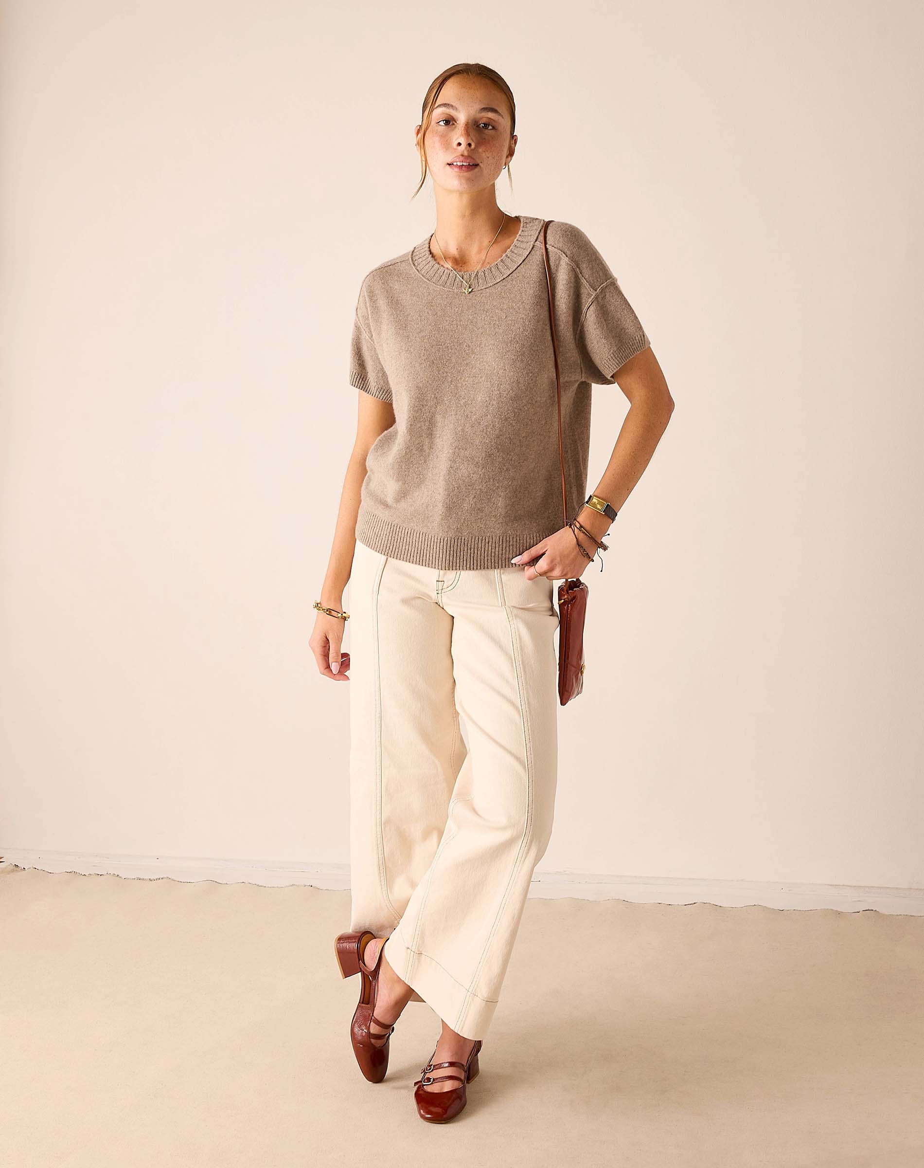Woman in a beige cashmere knit short-sleeve crewneck top and cream linen pants.