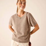 Woman in a beige short-sleeve cashmere crewneck knit top and cream-colored trousers.