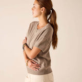 Woman in a beige cashmere crewneck short-sleeve knit top and cream-colored pants.