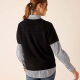 Model from behind wearing a black cashmere crewneck sweater over a light blue striped button-down shirt and jeans.