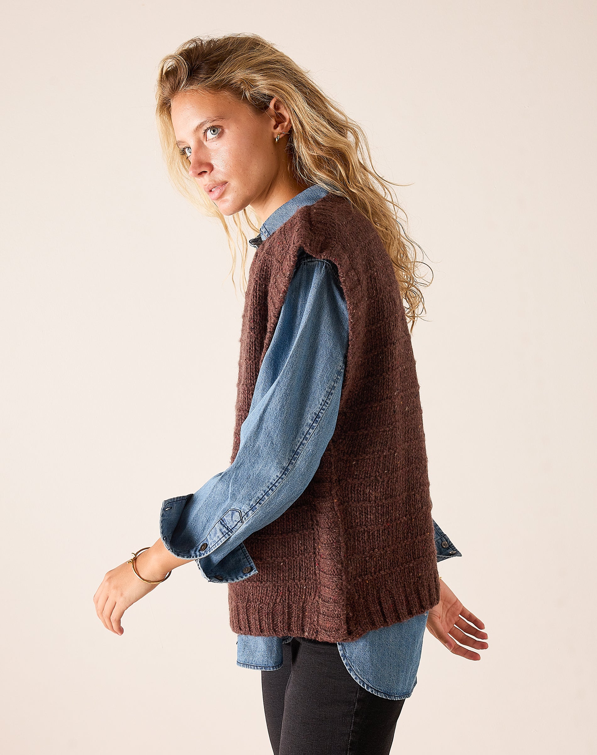 Chocolate brown ribbed knit sweater vest layered over a denim button-down shirt.