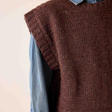 Chocolate brown knit sweater vest with a ribbed texture over a denim button-down shirt.