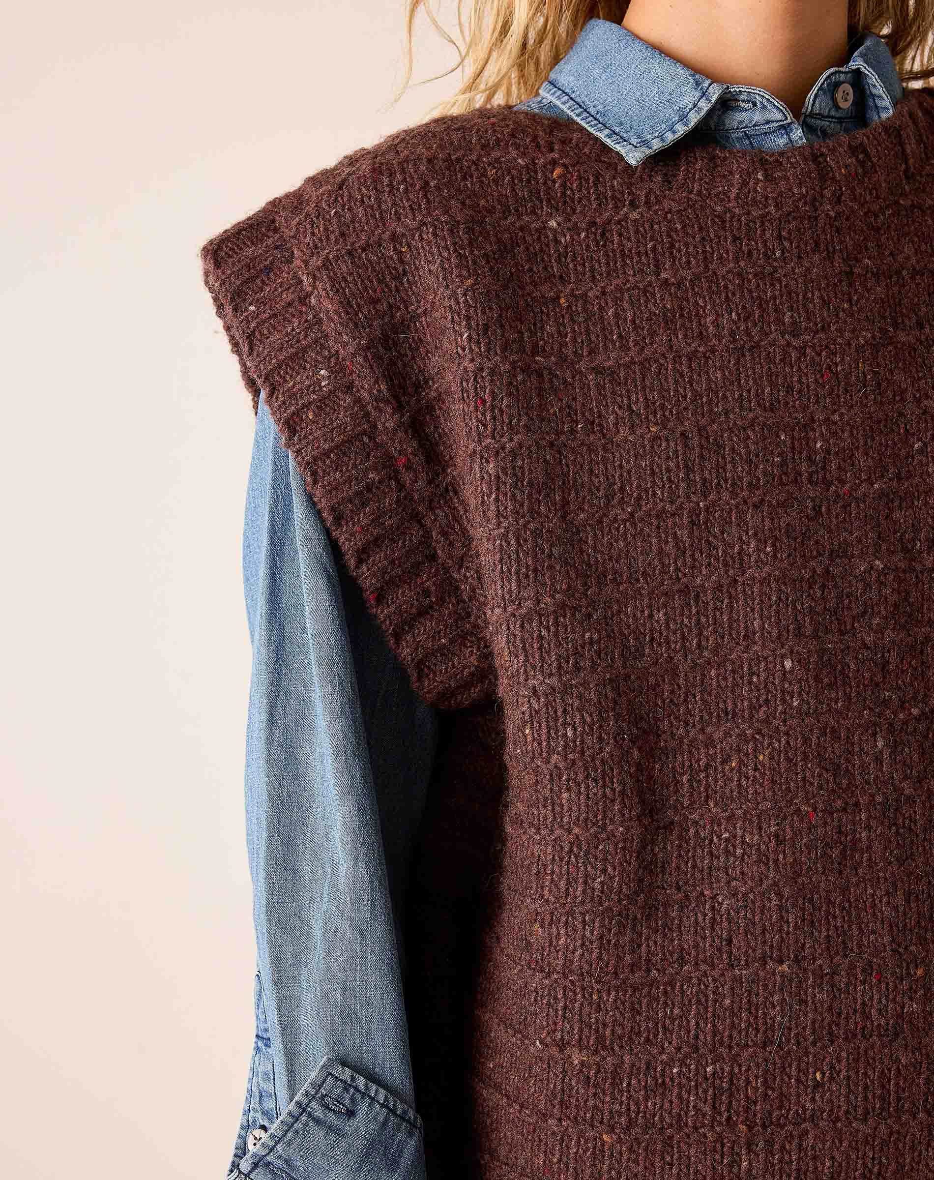 Chocolate brown knit sweater vest with a ribbed texture over a denim button-down shirt.