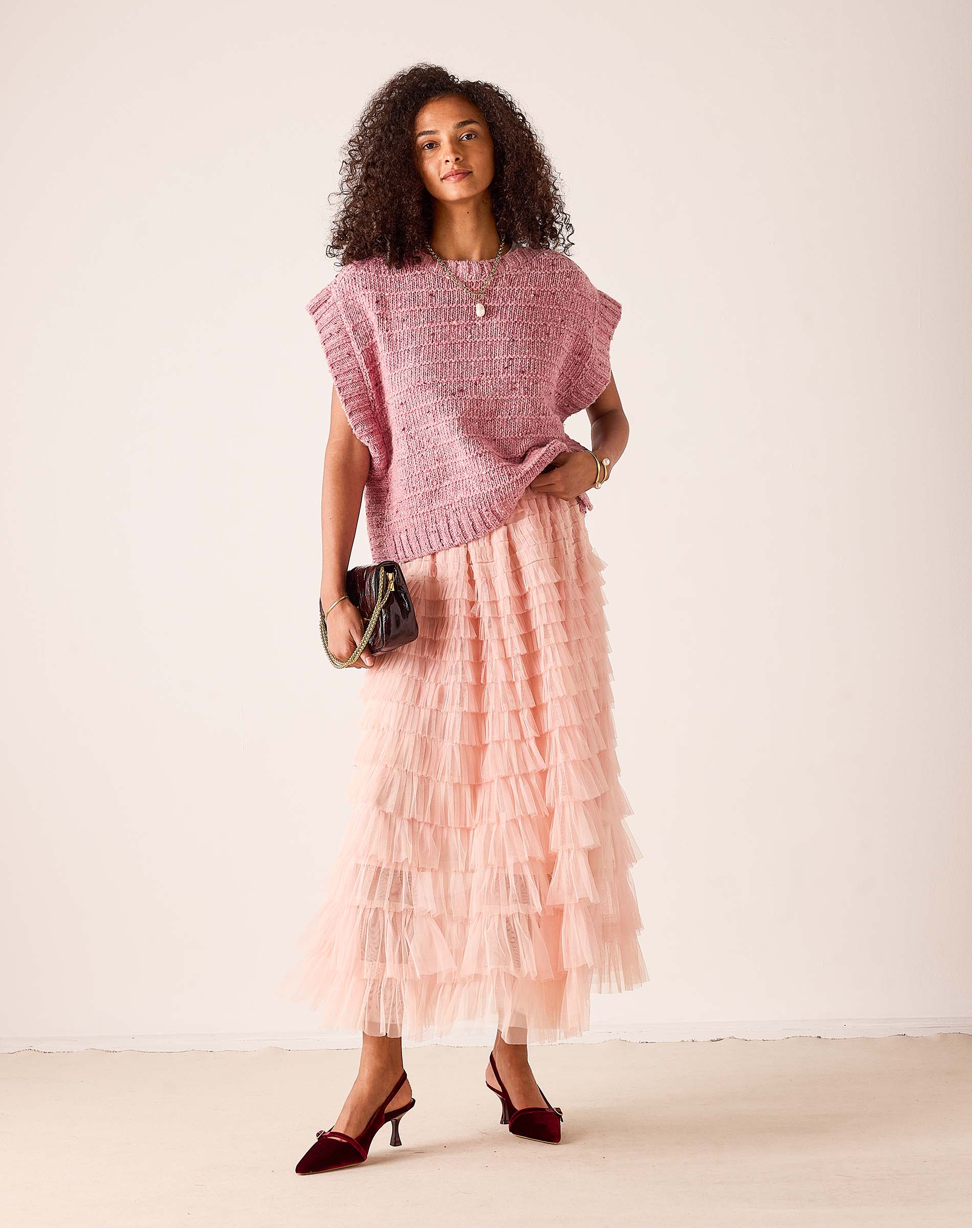 Ladies' travel-ready rose pink oversized knit sweater vest layered over a tiered ruffle maxi skirt.