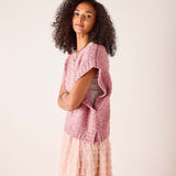 Rose pink knit sweater vest with a pointelle stitch pattern.