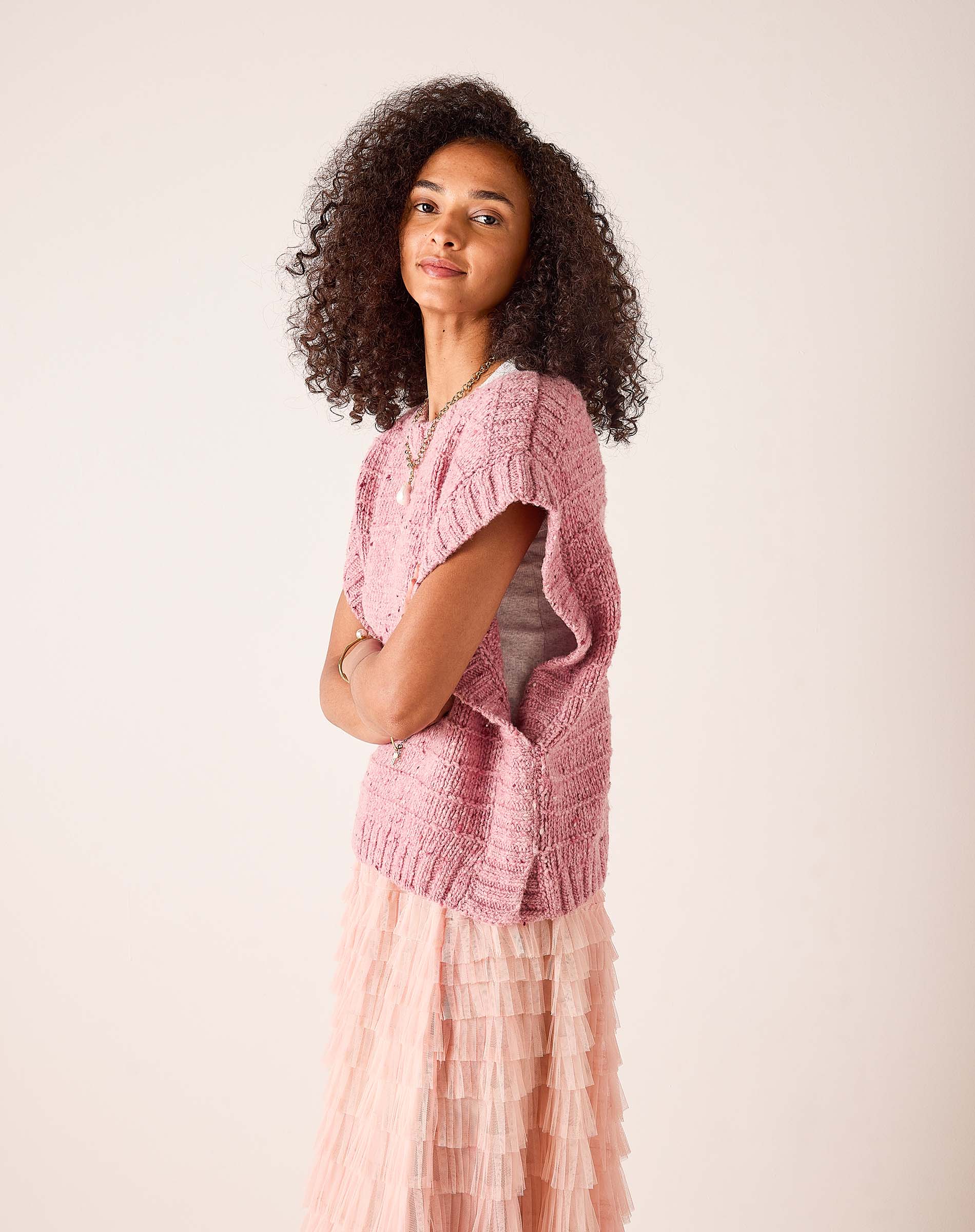 Rose pink knit sweater vest with a pointelle stitch pattern.