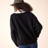 Back view of women's travel-friendly black oversized cashmere knit v-neck sweater with drop shoulder seams.