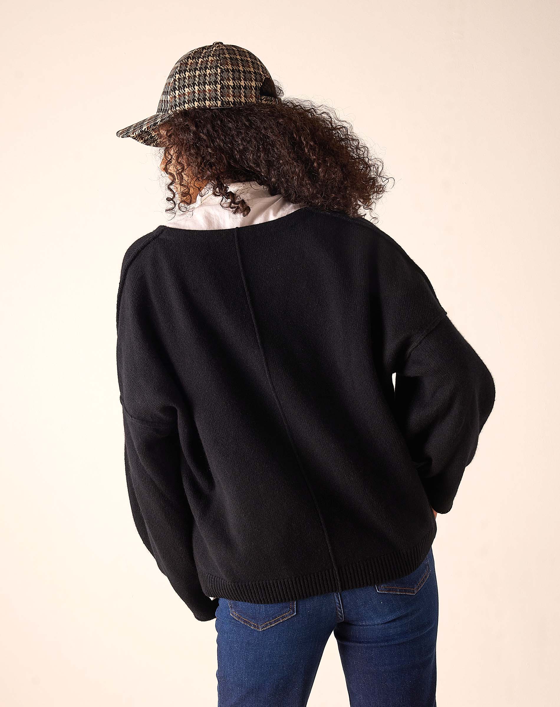 Back view of women's travel-friendly black oversized cashmere knit v-neck sweater with drop shoulder seams.