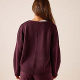 Back view of women's travel-friendly plum cashmere v-neck knit sweater with a relaxed fit and ribbed hem.