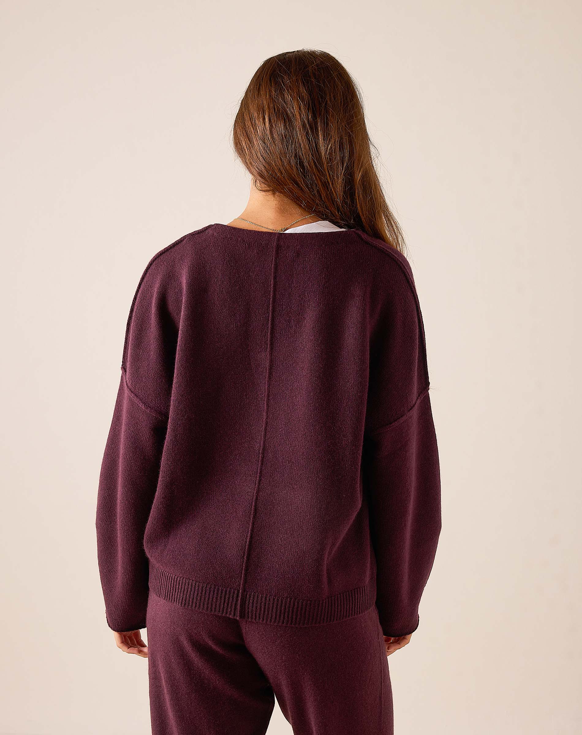 Back view of women's travel-friendly plum cashmere v-neck knit sweater with a relaxed fit and ribbed hem.
