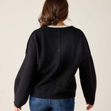 Person wearing a black sweater and blue jeans on a plain background