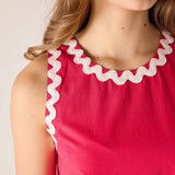 Red dress with white trim worn by a person on a plain background