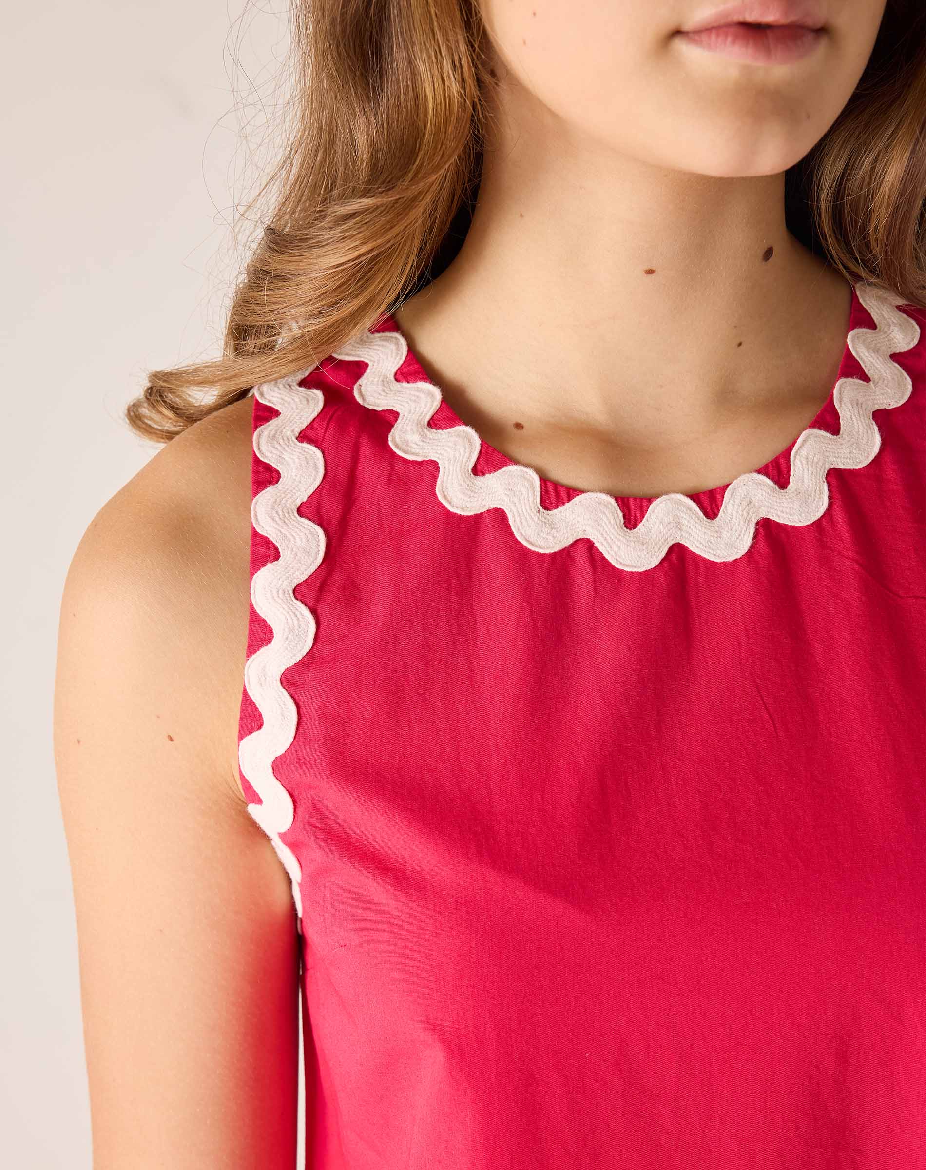 Red dress with white trim worn by a person on a plain background
