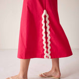 Red skirt with white ruffle trim worn by a person on a plain background