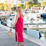 Woman in a pink dress walking along a harbor with boats in the background