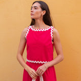 Woman wearing a red dress with white trim against a yellow wall