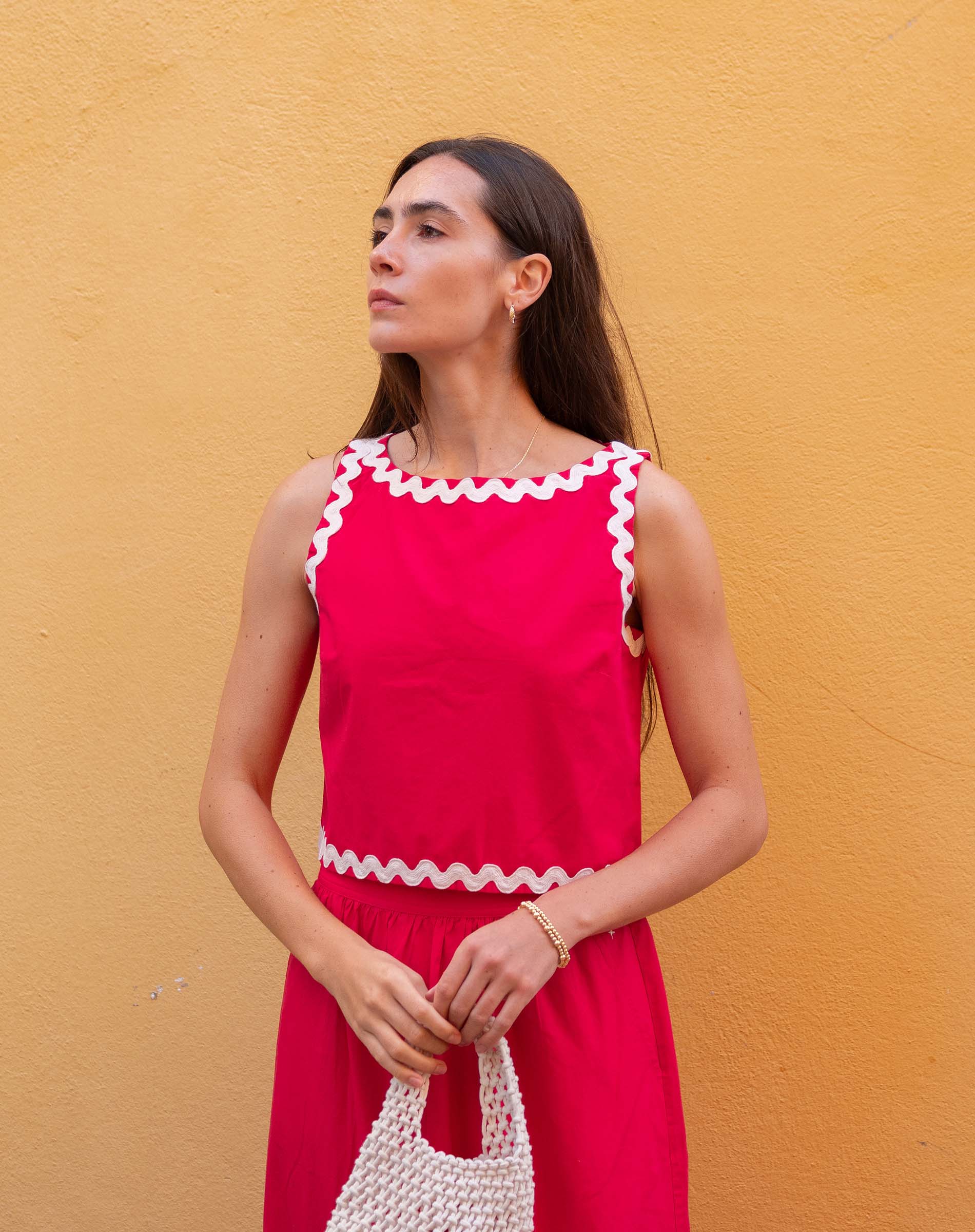 Woman wearing a red dress with white trim against a yellow wall