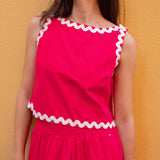 Woman wearing a pink dress with white trim against a yellow background