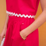Red dress with white trim on a person against an orange background