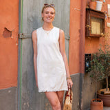 Woman in a white dress standing in front of a rustic building with orange walls.