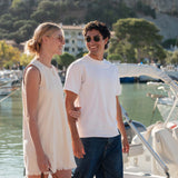 Two people standing on a dock with boats and a scenic background