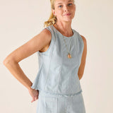 Woman wearing a light blue sleeveless top and pants against a beige background