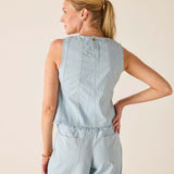 Woman wearing a light blue sleeveless top and pants against a beige background